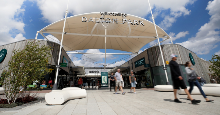 Entrance to Dalton Park shopping centre with people walking in and out holding shopping bags.